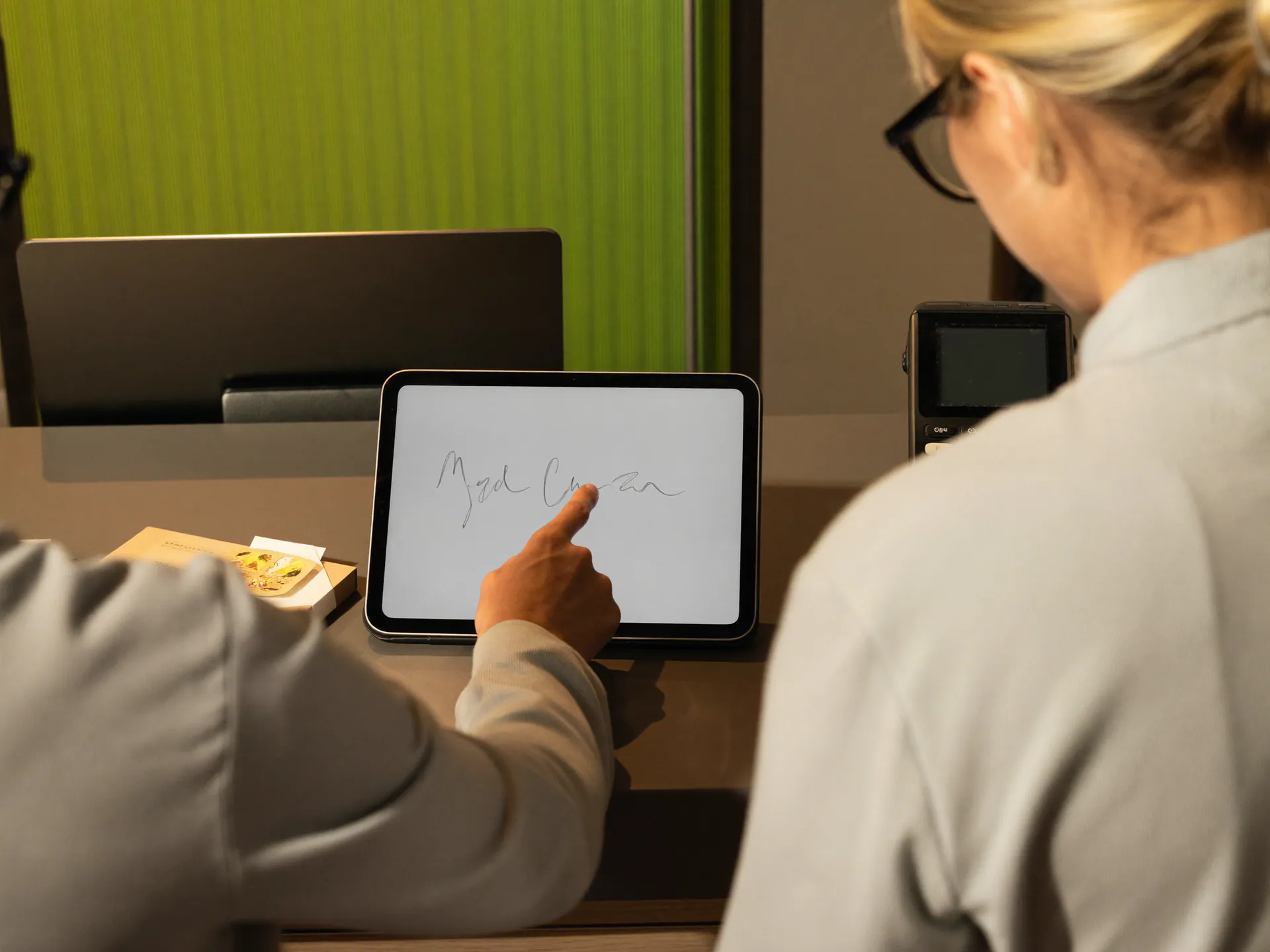Cliente che firma un documento sul tablet alla reception del centro